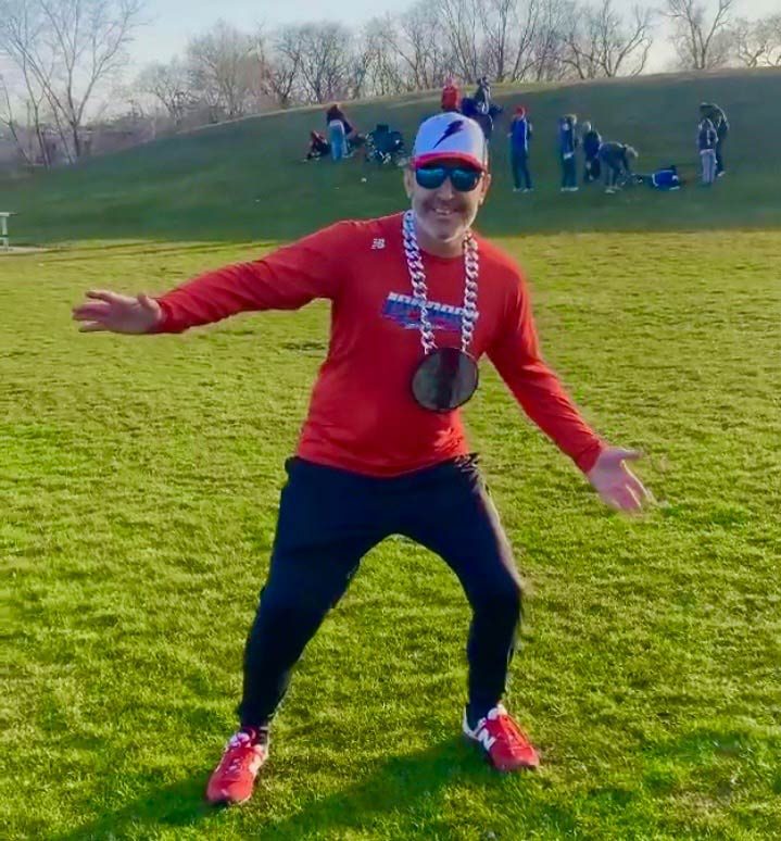Person wearing a dark round pendant on a sports field.
